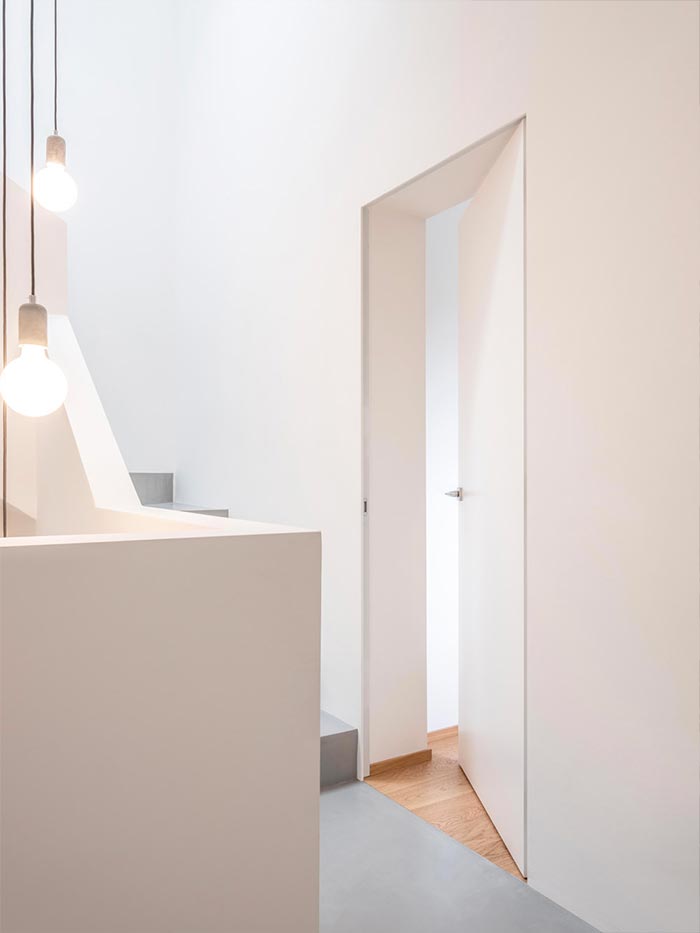 Tapétaajtó tiszta minimalista folyosón - függő lámpák, fehér falak